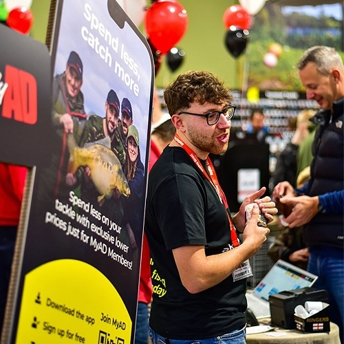 Sign promoting MyAD with Angling Direct store colleague stood to the right of it.